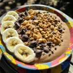 - 1 banana, frozen - 1 cup almond milk (or any milk of choice) - 3 tablespoons creamy peanut butter - 2 tablespoons cocoa powder - 1 tablespoon honey or maple syrup (optional) - 1/2 cup Greek yogurt (optional for creaminess) - 1/4 cup granola - 2 tablespoons dark chocolate chips - 1 tablespoon crushed peanuts - Fresh banana slices and cocoa nibs for topping You can play with this smoothie bowl. Add your twist! Here are some ideas: - Swap almond milk for oat or coconut milk. - Use crunchy peanut butter for a fun texture. - Try adding a scoop of protein powder for extra energy. - Mix in spinach or kale for a green boost. - Top with fresh berries for added sweetness and color. Each ingredient adds something special. Here’s why they matter: - Banana: Packed with potassium, it helps your heart and muscles. - Almond Milk: Low in calories and rich in vitamins, it’s a smart choice. - Peanut Butter: Full of protein and healthy fats, it keeps you full. - Cocoa Powder: Contains antioxidants that may boost your mood. - Greek Yogurt: Adds probiotics for gut health and extra creaminess. - Granola: Provides fiber and energy to start your day right. - Dark Chocolate: Offers a touch of sweetness and rich flavor while being lower in sugar than milk chocolate. With these ingredients, you get a tasty and healthy bowl! Enjoy the flavors and the nutrition they bring. 1. First, gather your ingredients. You need: - 1 frozen banana - 1 cup almond milk (or any milk of choice) - 3 tablespoons creamy peanut butter - 2 tablespoons cocoa powder - 1 tablespoon honey or maple syrup (optional) - 1/2 cup Greek yogurt (optional for creaminess) - 1/4 cup granola - 2 tablespoons dark chocolate chips - 1 tablespoon crushed peanuts - Fresh banana slices and cocoa nibs for topping 2. In a blender, combine the frozen banana, almond milk, peanut butter, and cocoa powder. If you want sweetness, add honey or maple syrup. 3. Next, if you like creaminess, toss in the Greek yogurt. 4. Blend everything on high until it gets smooth and creamy. If it’s too thick, add more almond milk to reach your desired texture. 5. Pour the smoothie into a bowl. To get the best texture, start with the liquids first. This helps the blender run smoothly. If your blender struggles, stop and mix with a spoon. Blend it again until smooth. For a thicker smoothie, use less almond milk. When serving, make it look pretty! Top the smoothie with: - Granola for crunch - Dark chocolate chips for sweetness - Crushed peanuts for extra flavor Garnish with fresh banana slices and a sprinkle of cocoa nibs. For a fun touch, drizzle extra peanut butter on top. Serve it on a colorful plate for a nice pop! Enjoy your tasty treat! To get the best texture, start with frozen bananas. They add creaminess and chill. Use almond milk, or your favorite milk, to blend. Add it gradually. If you want a thicker bowl, use less milk. For a creamier feel, add Greek yogurt. Blend until smooth. If it’s too thick, add a splash more milk. Toppings make your smoothie bowl fun and tasty. Try using granola for crunch. Dark chocolate chips add sweetness. Crushed peanuts give a nice, nutty flavor. Fresh banana slices look great and taste good. Cocoa nibs add a bit of crunch and a chocolatey taste. Arrange your toppings in a colorful way, as it makes the bowl more appealing. If you have leftover smoothie, store it right. Pour it into an airtight container. Keep it in the fridge for up to one day. Stir it well before eating. For longer storage, freeze it in ice cube trays. This way, you can use it later in other smoothies or bowls. Just blend the frozen cubes when you're ready to enjoy! {{image_2}} You can turn your Peanut Butter Cup Smoothie Bowl into a chocolate lover's dream. Just add extra cocoa powder. Use two tablespoons instead of one. This boosts the chocolate flavor and makes it even richer. You can also add chocolate protein powder if you want more protein. Blend it all together for a tasty treat. If you want a vegan version, swap Greek yogurt for a plant-based yogurt. Almond milk works great, but any nut milk is fine. You can also use maple syrup instead of honey. Make sure your chocolate chips are dairy-free. This way, everyone can enjoy this smoothie bowl. For a protein boost, mix in some protein powder. You can choose any flavor you like. Another option is to add a tablespoon of chia seeds. This gives you extra fiber and protein. If you want more crunch, toss in some nuts or seeds. This way, you make your smoothie bowl filling and nutritious. If you have leftover smoothie bowl, store it in an airtight container. Make sure to cover it well. This keeps the flavors fresh and prevents oxidation. Place it in the fridge. It will stay good for one day. Stir it well before eating. If it thickens, add a splash of milk to loosen it. You can freeze parts of the smoothie bowl. For example, freeze extra bananas or peanut butter. Store them in freezer bags. Remove the air and seal tightly. When you want to make another bowl, just blend them straight from the freezer. This saves time and makes it easy to whip up a treat. Most ingredients in this recipe have a good shelf life. - Frozen bananas can last up to six months. - Almond milk stays fresh for about seven to ten days once opened. - Peanut butter can be good for several months, even up to a year if unopened. - Cocoa powder remains fresh for about two to three years if stored in a cool, dry place. - Greek yogurt lasts about one week in the fridge after opening. By knowing how to store and freeze these ingredients, you can enjoy your peanut butter cup smoothie bowl anytime! Yes, you can use fresh bananas. However, frozen bananas give a thicker texture. They also make the smoothie cool and creamy. If you choose fresh, add ice to your blender. This keeps the smoothie bowl cold and enjoyable. You have many options if you need a peanut butter substitute. Almond butter, cashew butter, or sun butter all work well. Each option has a unique taste, so pick one you like. If you want a nut-free option, try tahini or coconut cream. Yes, this smoothie bowl is great for meal prep. You can blend the base and store it in the fridge for up to 24 hours. Just add your toppings when you're ready to eat. This keeps the granola and bananas fresh and crunchy. This blog shared key steps to make a delicious smoothie bowl. We covered main ingredients, their health benefits, and how to blend them to get the perfect texture. You now know tips for serving and storing your leftovers. You can also explore tasty variations, including vegan options. Finally, answers to common questions help clear any confusion. Enjoy creating your smoothie bowl and customizing it to your taste! Feel excited to try new flavors and make this treat your own.
